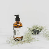 Broken Top Brands Sea Salt Surf Hand Soap bottle beside Spanish moss on a marble surface