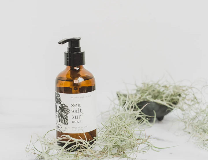 Broken Top Brands Sea Salt Surf Hand Soap bottle beside Spanish moss on a marble surface