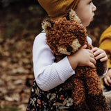 Child in a yellow hat hugging the Bunnies By The Bay Foxy The Fox Plush among autumn leaves