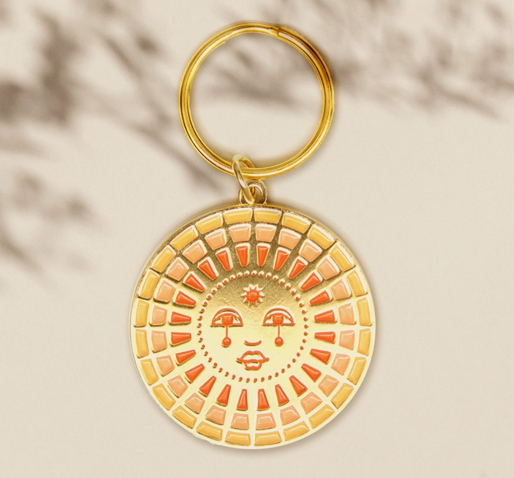 Cai & Jo Keychain, a round gold enamel sun face charm in orange and cream on a gold ring