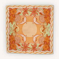Cai & Jo Tavarua Bandana, an orange and sage bandana with dolphins, hibiscus and shells around a sun