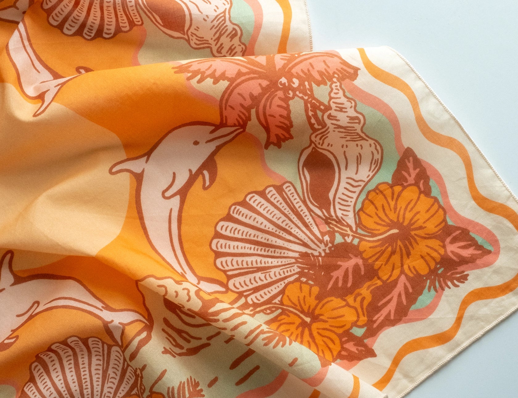 Close-up of the dolphin and hibiscus print on the Cai & Jo Tavarua Bandana