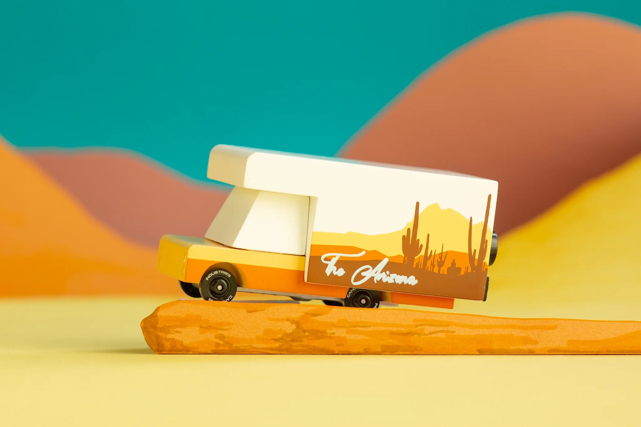 Candylab Toys Arizona Wooden RV toy camper on an orange desert-styled backdrop with teal sky