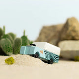 Candylab Toys Mini Zebra Drifter on sand beside a toy cactus and rocks