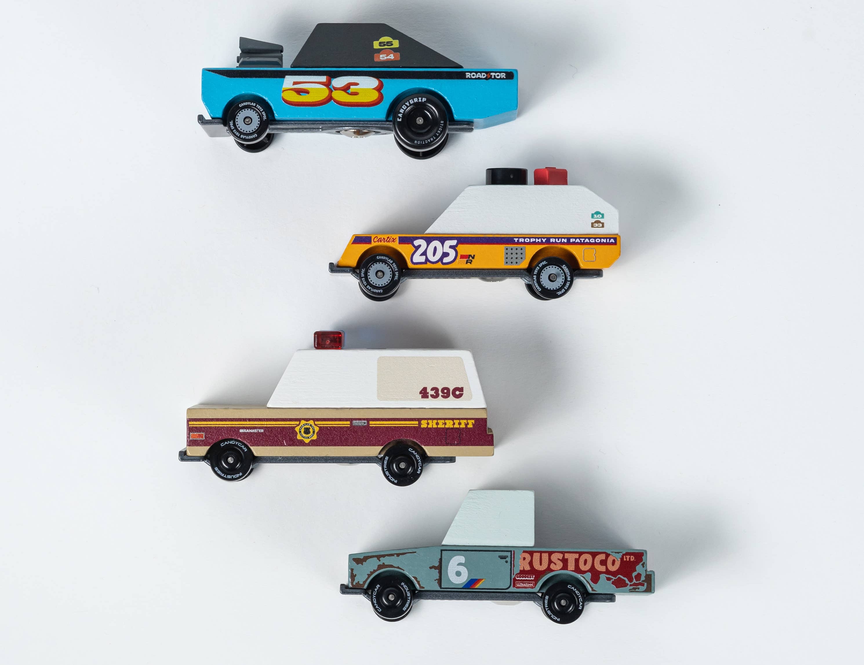 Candylab Toys Rust Patrol TOONS 4-Pack, four wooden toy vehicles: a blue race car, orange sheriff, tan patrol truck and gray pickup