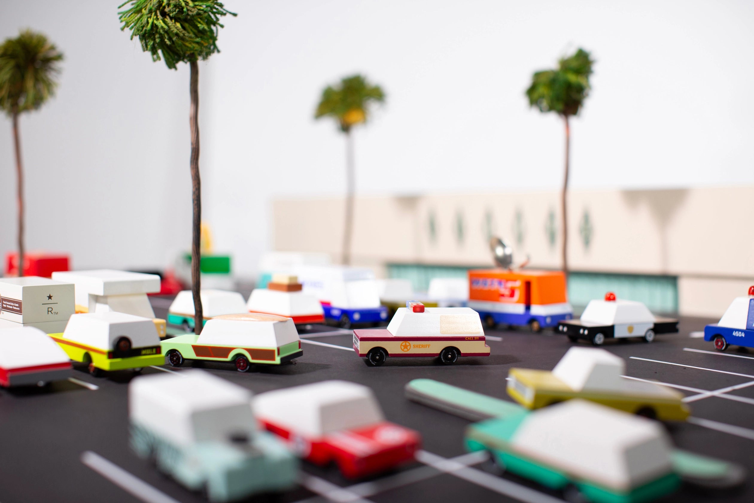 Candylab Toys Sheriff Truck in a toy parking lot with other wooden cars and palm trees