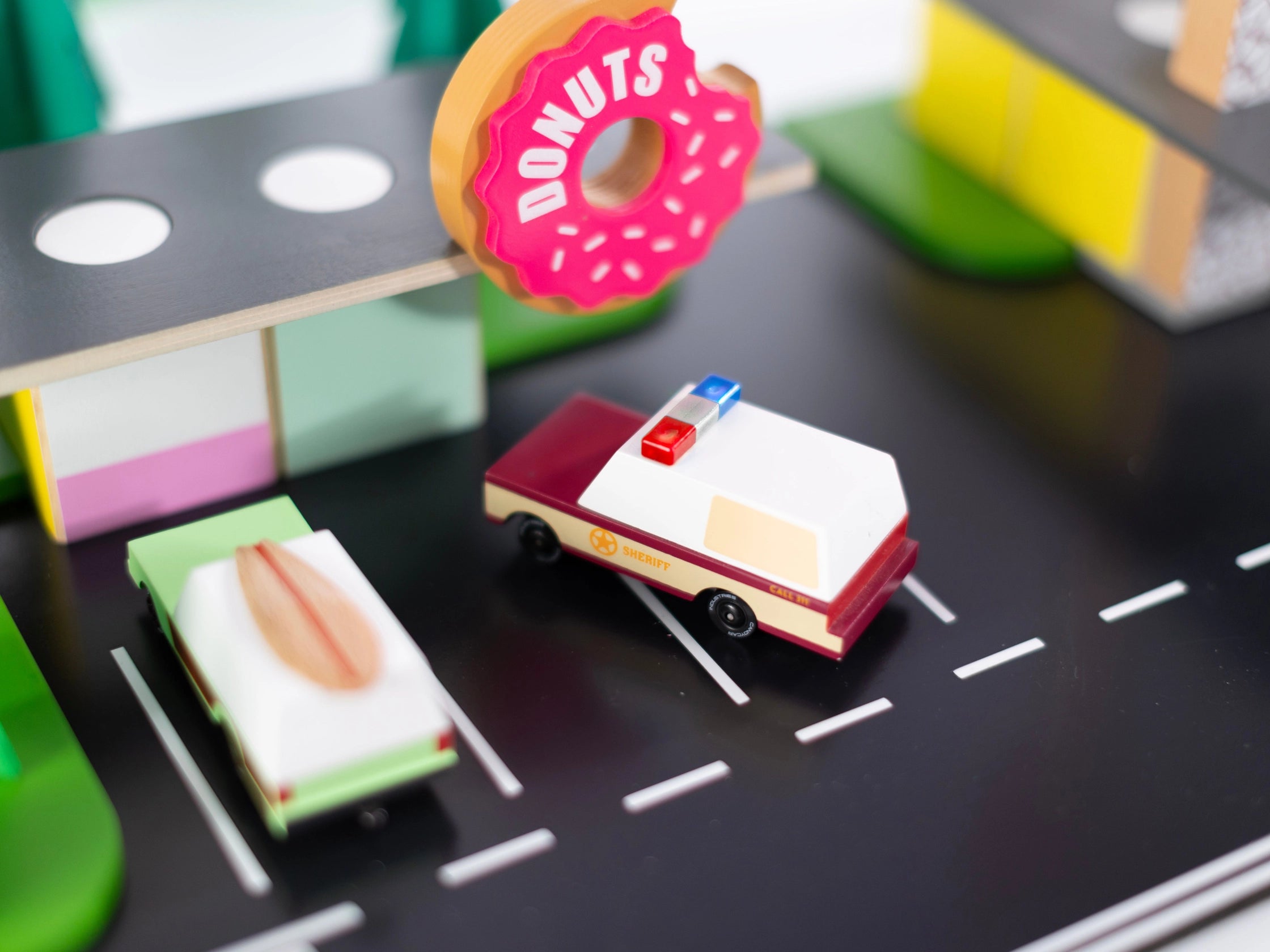 Candylab Toys Sheriff Truck on a toy road scene beside a donut shop and food trucks