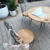 The Canyon Rose tote leaning against a bistro chair on a greenhouse patio, with an open notebook on the table.