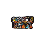 Canyonlands nameplate patch, CANYON LANDS embroidered in two rows of block letters with canyon scenery inside each letter, black merrowed border.
