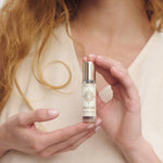 Woman in a cream top holding the Cast of Stones Calming Roll On Aromatherapy oil