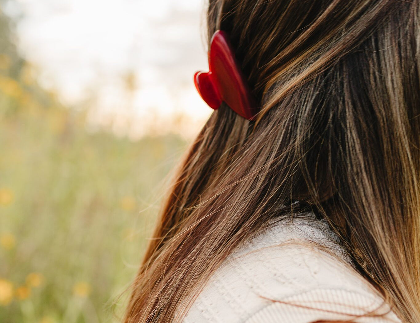 The Garnet Classic claw clip in deep red holding a half up section of long brown hair.