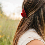 The Garnet Classic claw clip in deep red holding a half up section of long brown hair.