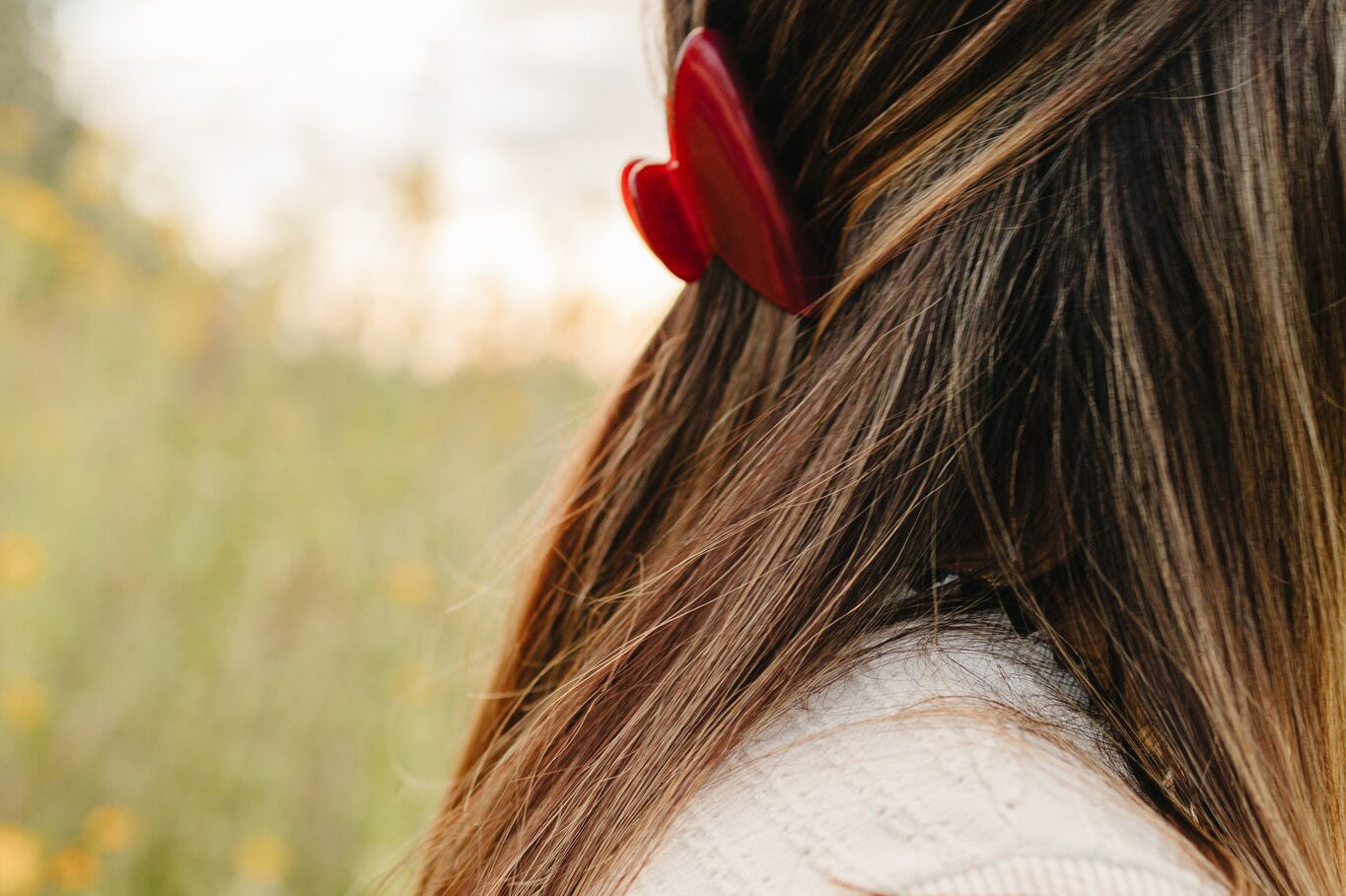 The Garnet Classic claw clip in deep red holding a half up section of long brown hair.