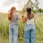 Two women standing in tall grass at sunset, each wearing a Classic claw clip in a half up style.