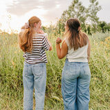 Two women standing in tall grass at sunset, each wearing a Classic claw clip in a half up style.