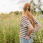 A woman in a wildflower field wearing a soft sage Classic claw clip in a half up style.