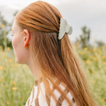 The Muted Moss Classic claw clip in soft green holding a half up section of long blonde hair.