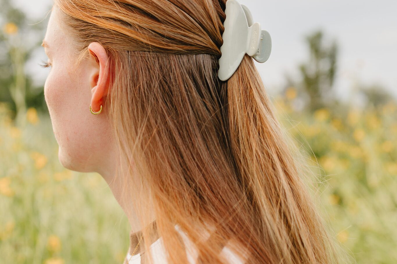 The Muted Moss Classic claw clip in soft green holding a half up section of long blonde hair.