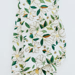 Clementine Kids Magnolia Swaddle Blanket, a white muslin swaddle with a green and white magnolia print, close-up