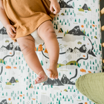 Baby in a mustard romper lying on the Clementine Kids National Parks Crib Sheet