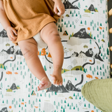 Baby in a mustard romper lying on the Clementine Kids National Parks Crib Sheet