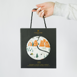 Clementine Kids National Parks Crib Sheet in its black gift bag with a circular window
