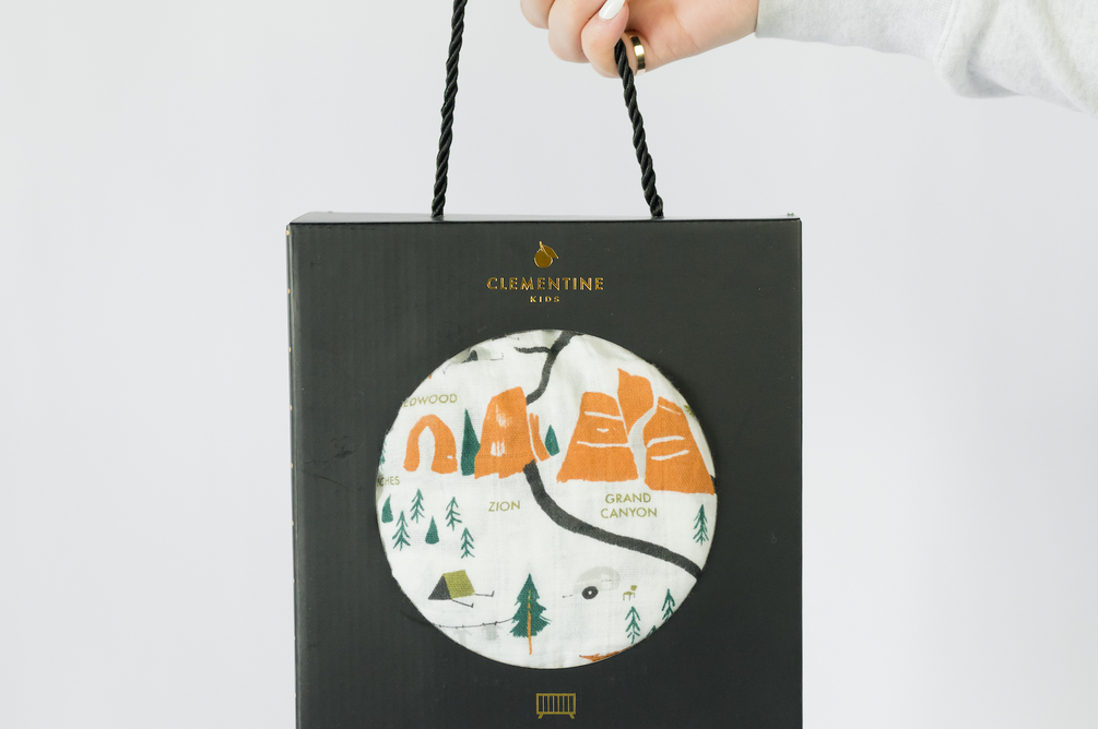 Clementine Kids National Parks Crib Sheet in its black gift bag with a circular window