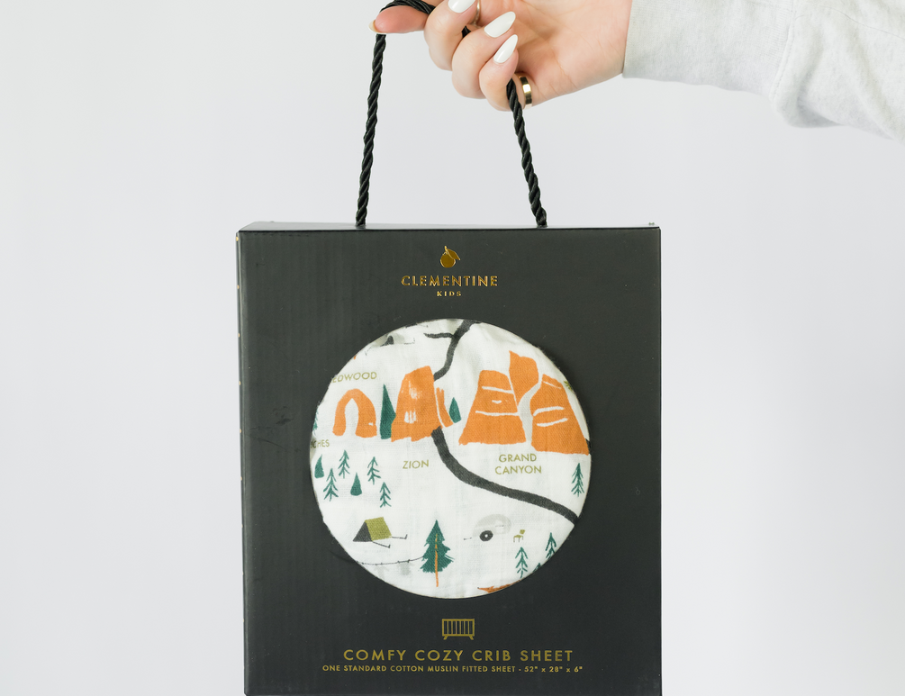 Clementine Kids National Parks Crib Sheet in its black gift bag with a circular window