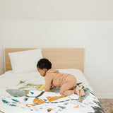 Toddler crawling on the Clementine Kids National Parks Throw Blanket spread across a bed