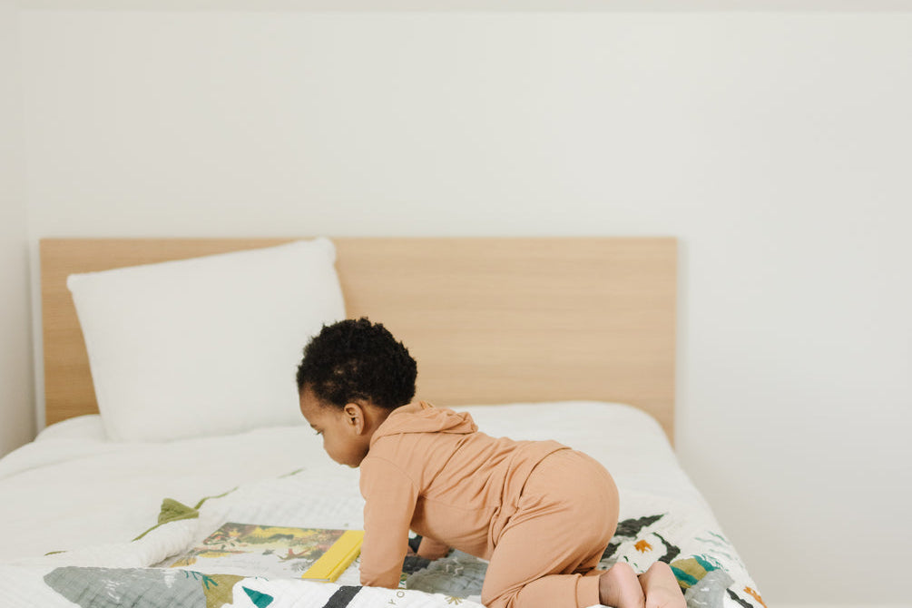 Toddler crawling on the Clementine Kids National Parks Throw Blanket spread across a bed