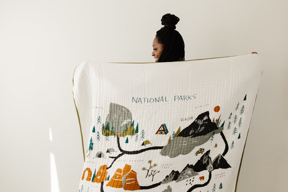 Clementine Kids Large Reversible National Parks Throw Blanket held up showing the illustrated parks map