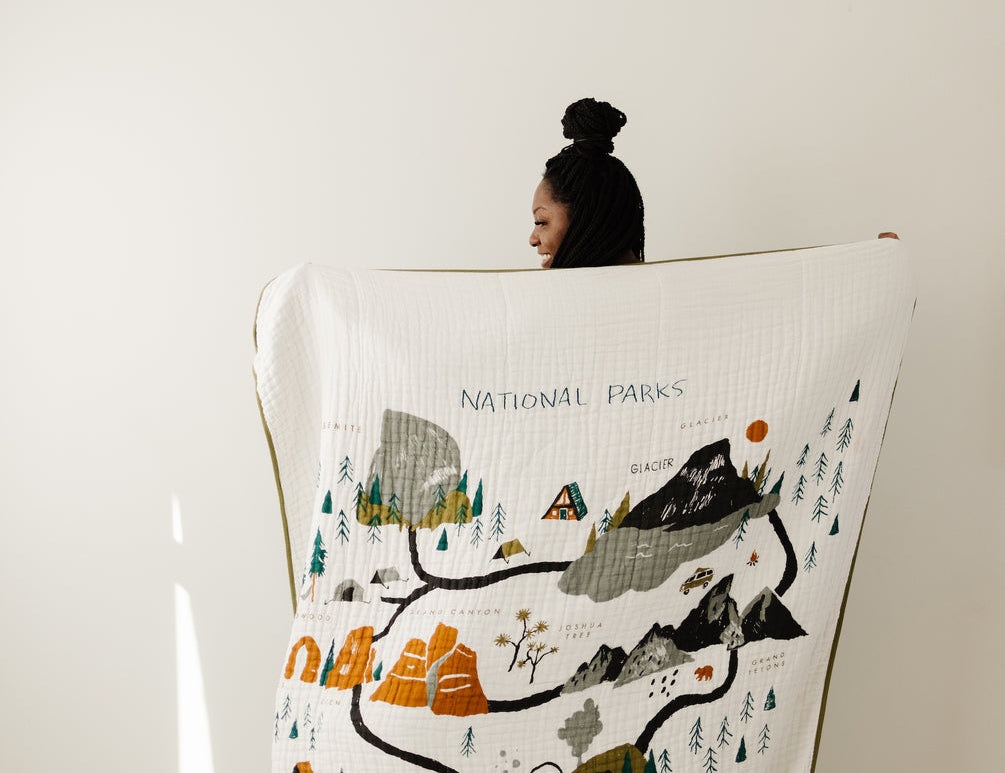 Clementine Kids Large Reversible National Parks Throw Blanket held up showing the illustrated parks map