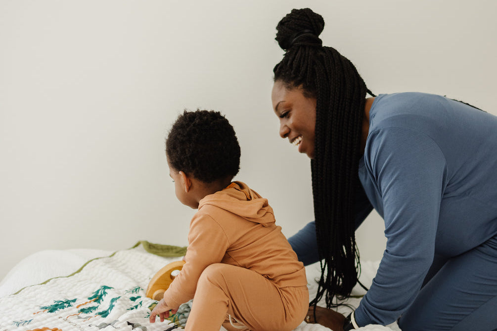 Mother and child playing on the Clementine Kids National Parks Throw Blanket on a bed