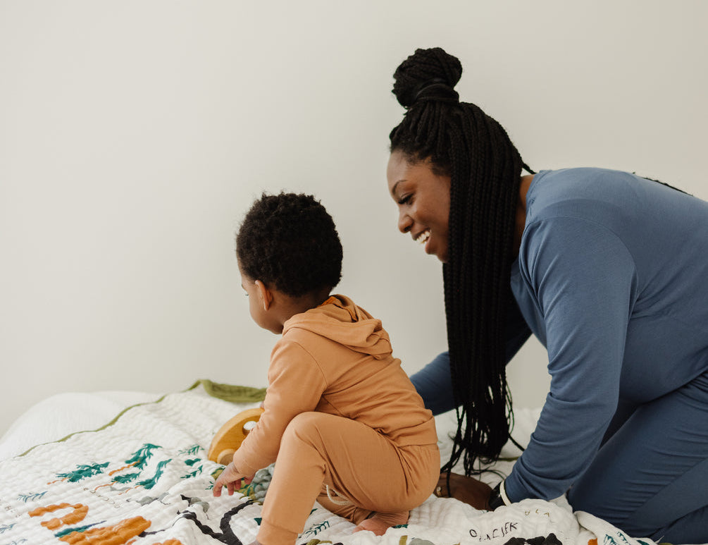 Mother and child playing on the Clementine Kids National Parks Throw Blanket on a bed