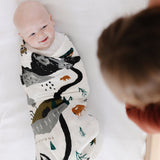Smiling baby swaddled in the Clementine Kids National Parks Swaddle