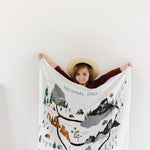Child in a sun hat holding up the Clementine Kids National Parks Swaddle