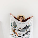 Child in a sun hat holding up the Clementine Kids National Parks Swaddle