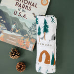 Clementine Kids National Parks Swaddle folded beside a National Parks of the USA book and pinecones