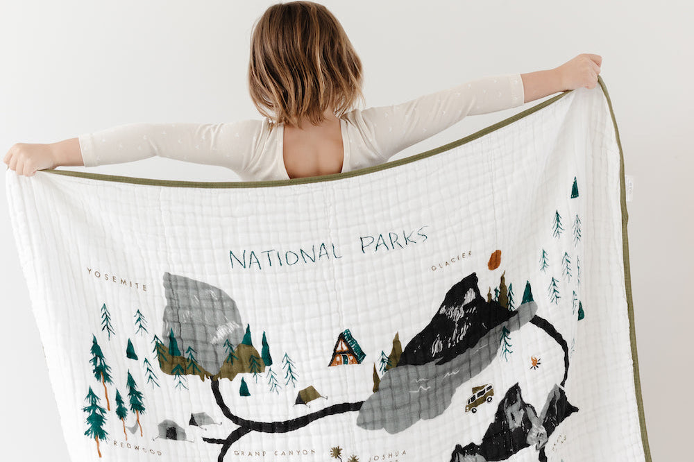 Child holding up the Clementine Kids Reversible National Parks Quilt