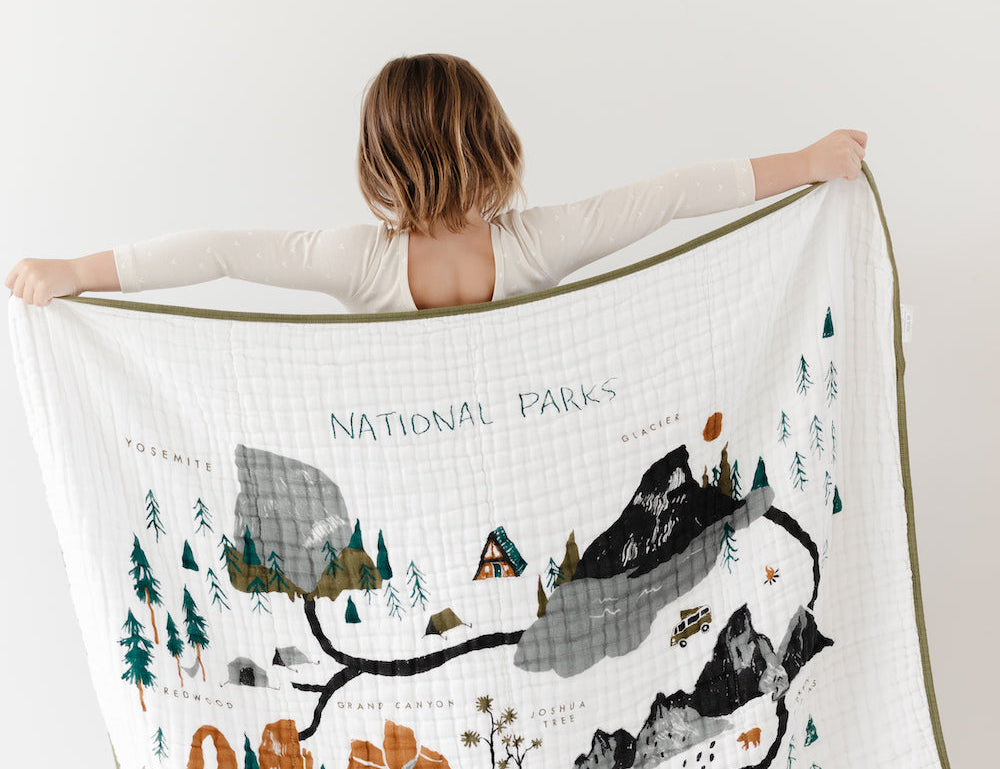 Child holding up the Clementine Kids Reversible National Parks Quilt