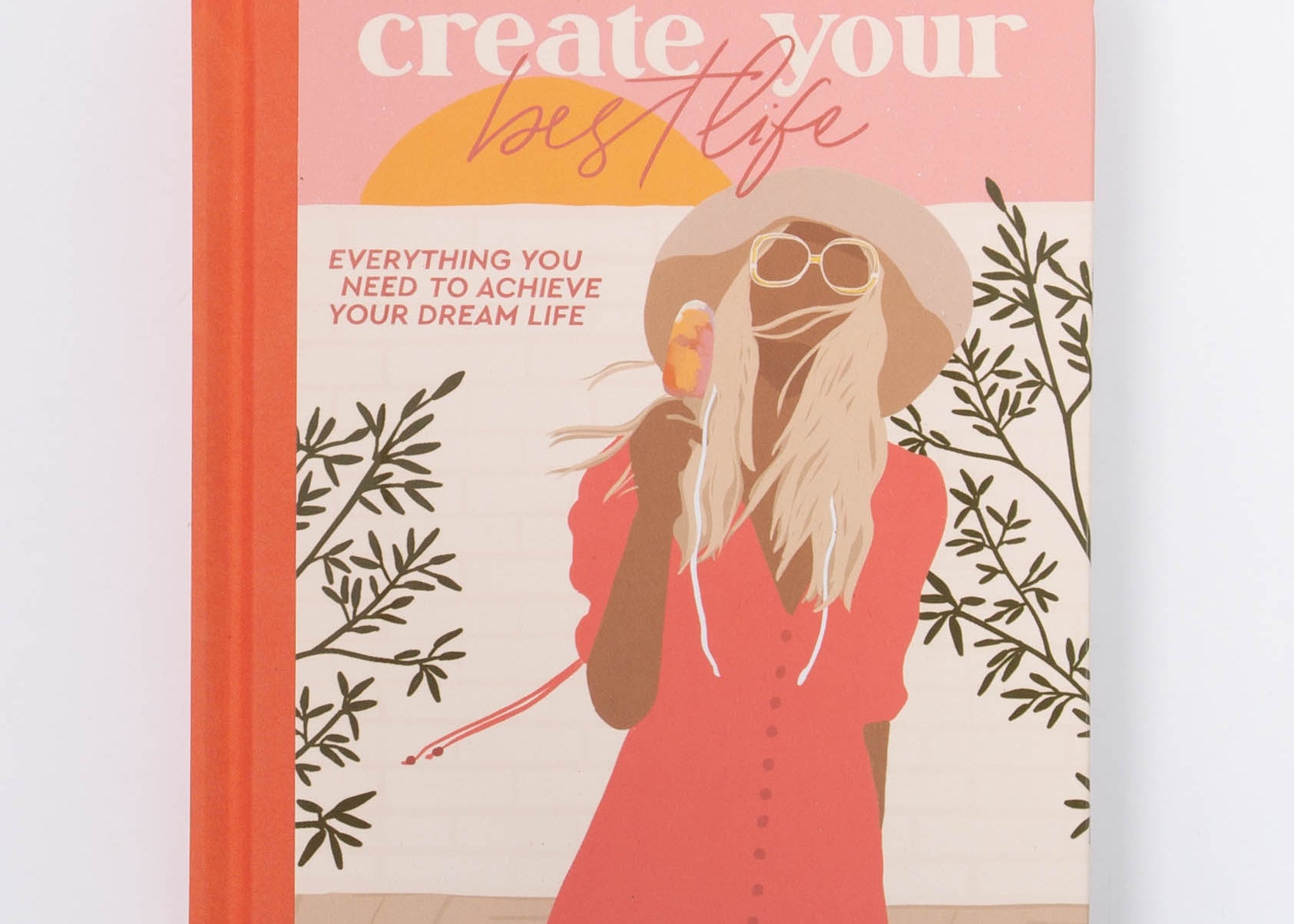 Collective Hub Create Your Best Life Journal, a coral hardcover with an illustrated woman in a red dress