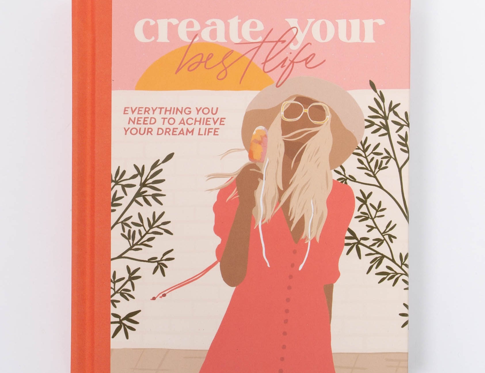 Collective Hub Create Your Best Life Journal, a coral hardcover with an illustrated woman in a red dress