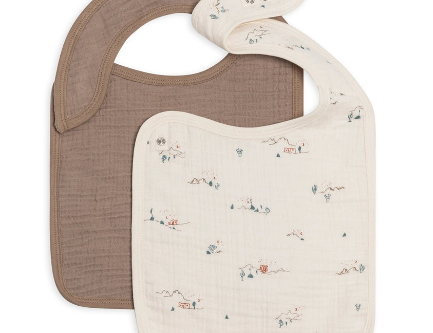 Colored Organics 2-Pack Muslin Bib in Desert and Taupe, one solid taupe bib and one ivory bib with a tiny desert cactus print, on white