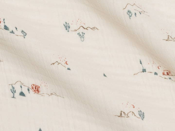 Close-up of the tiny cactus and mountain print on the Colored Organics Organic Muslin Swaddle Blanket in Desert