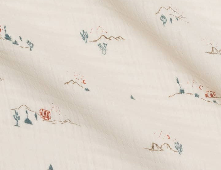 Close-up of the tiny cactus and mountain print on the Colored Organics Organic Muslin Swaddle Blanket in Desert