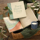 Compendium Every Reason to Hope book in a basket with a candle, blanket and greenery