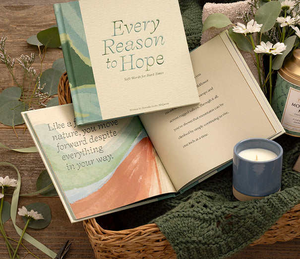 Compendium Every Reason to Hope book in a basket with a candle, blanket and greenery