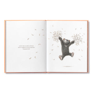 Compendium Feeling Grateful book open to an illustration of a bear holding a tree branch with falling leaves