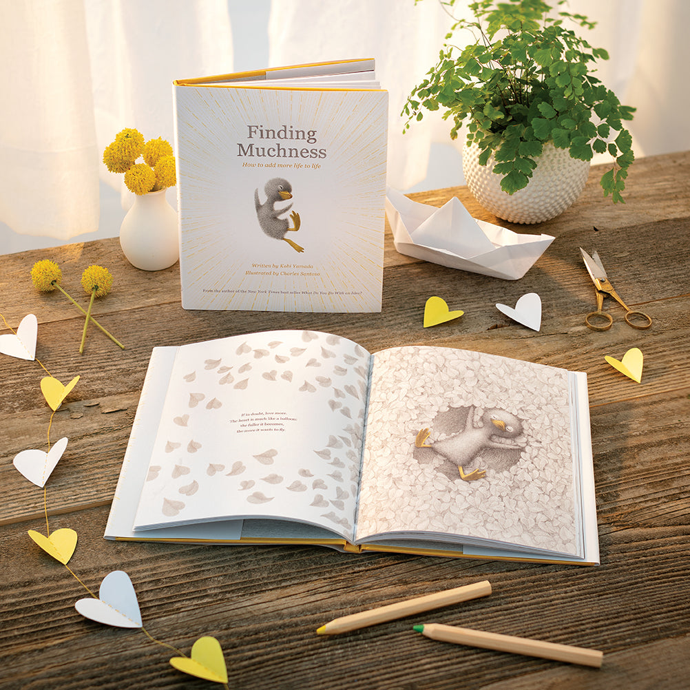 Compendium Finding Muchness book on a wooden table with an open copy, paper hearts and pencils