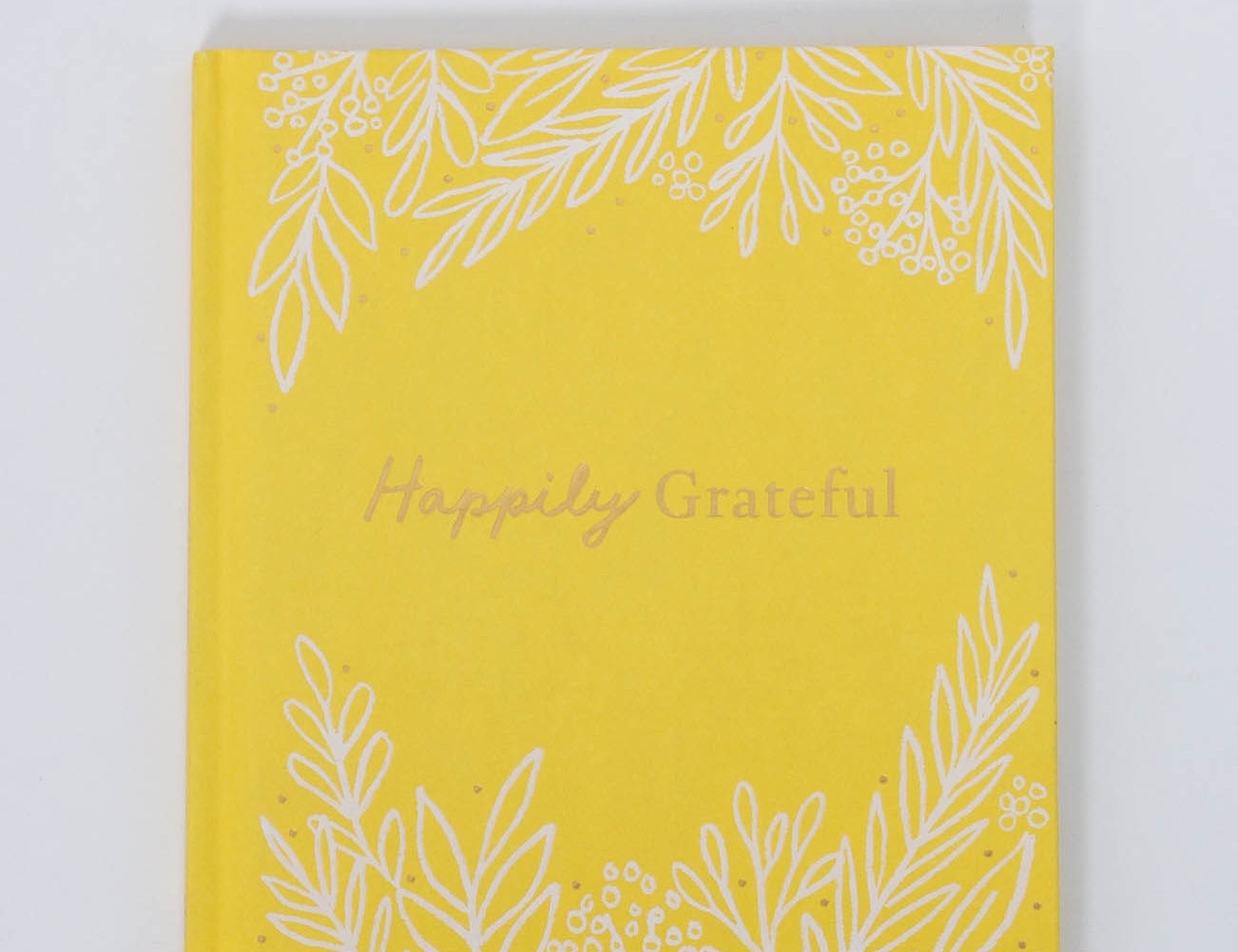 Compendium Happily Grateful book, a yellow linen cover with white botanical line art